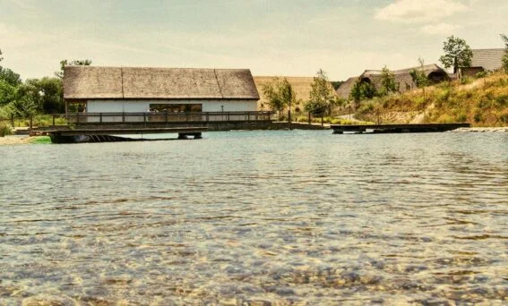 Tradiční dřevěná budova u vody v areálu Archeoskanzenu Modrá Ryba