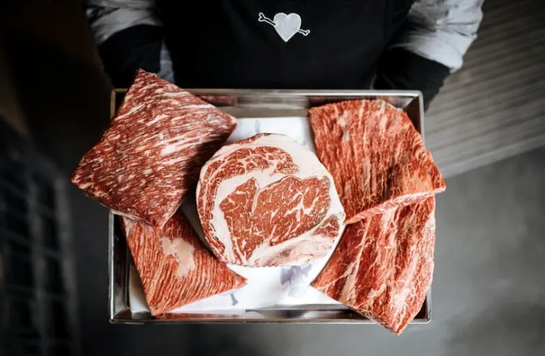 Tray s syrovým masem wagyu skotu s viditelnou mramorovostí.