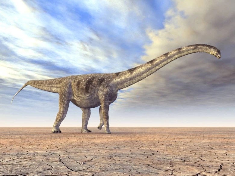 Velký dlouhokrký dinosaurus stojí na prasklé zemi pod oblohou.