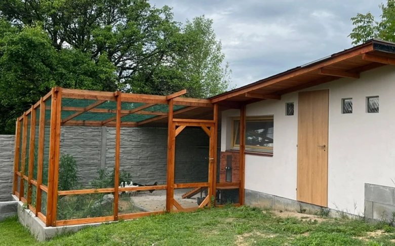 Dřevěný výběh pro slepice připojený k domu.