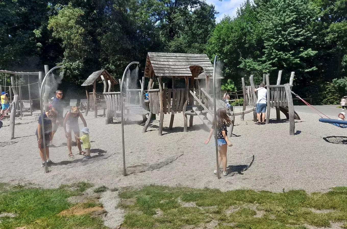 Děti hrají na venkovním hracím areálu s mlžícími oblouky.